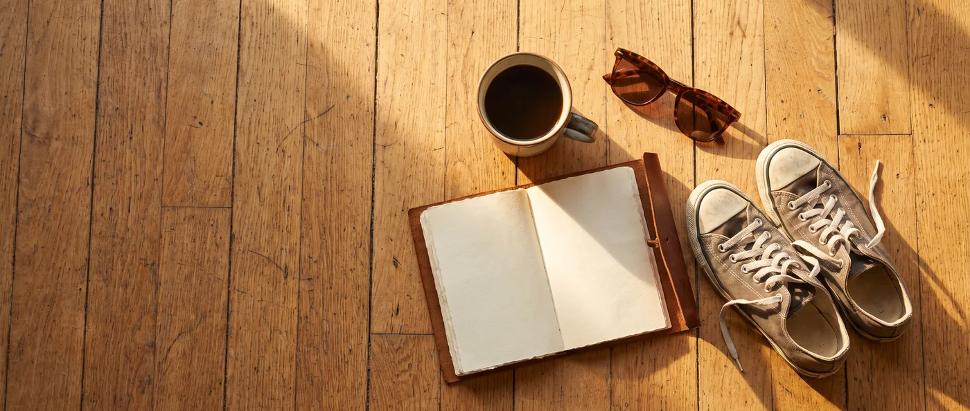 A morning-routine flat lay: coffee, an open journal, sneakers and sunglasses