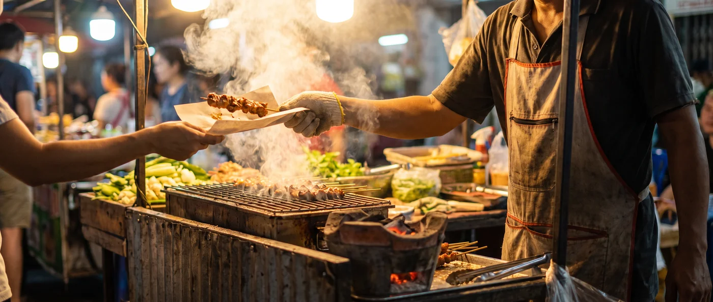 A night-market vendor handing over a sizzling skewer